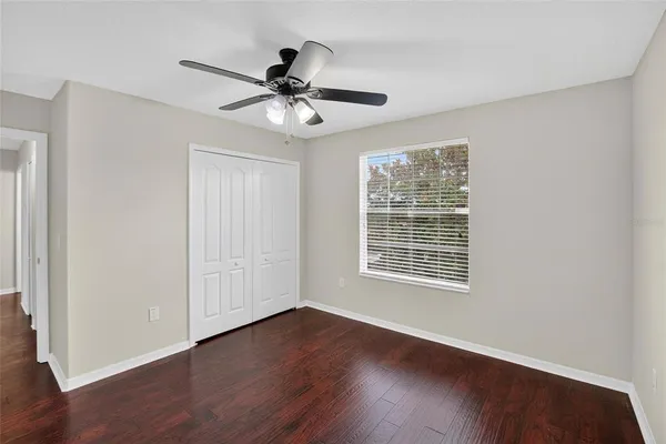 an empty room with wooden floor fan and windows