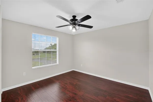 an empty room with wooden floor and ceiling fan