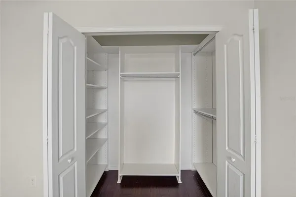 an empty room with wooden floor and a ceiling fan