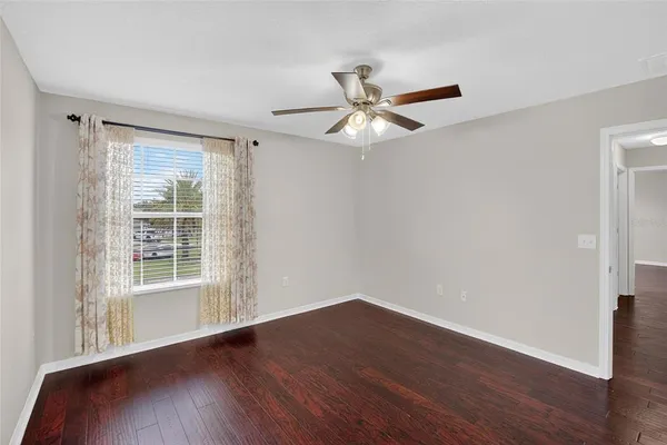 a view of an empty room with a window and wooden floor