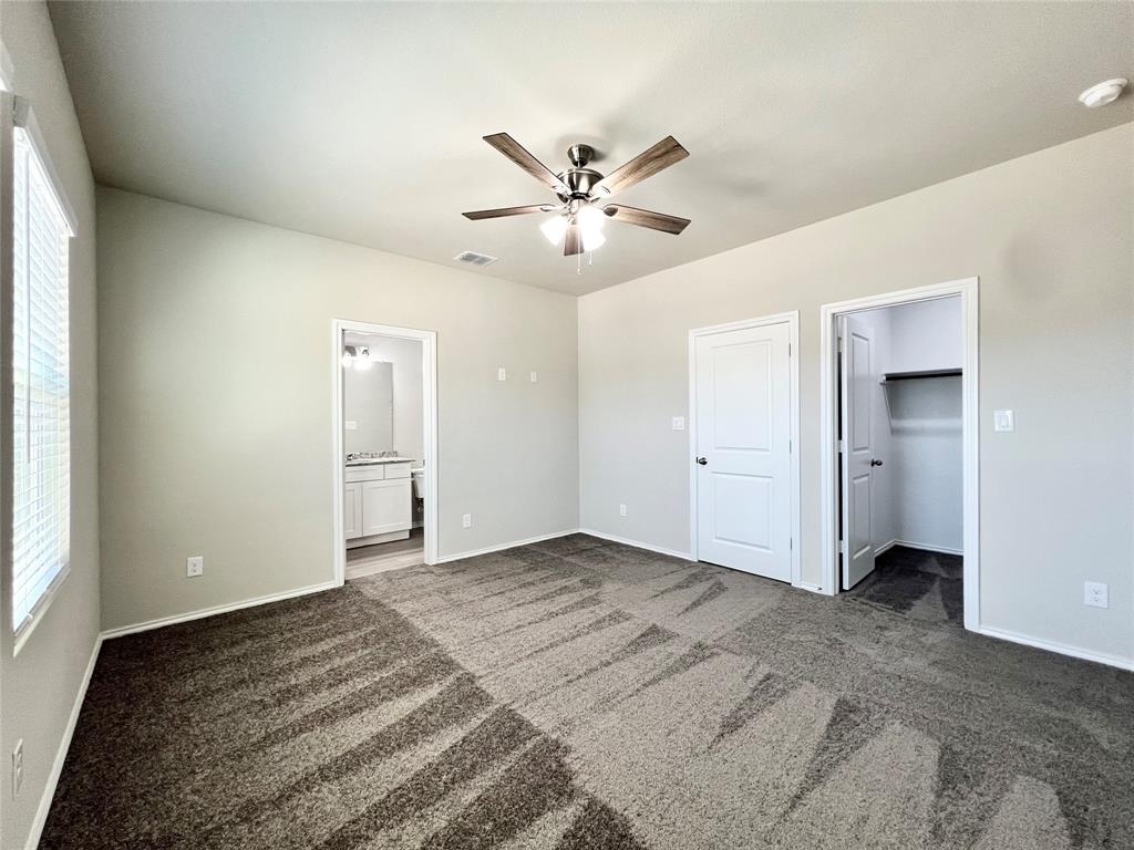 3501 East Renfro Street, Unit 122 Burleson, TX 76028 - Photo 16 of 29 Unfurnished bedroom featuring dark colored carpet, a spacious closet, connected bathroom, and ceiling fan