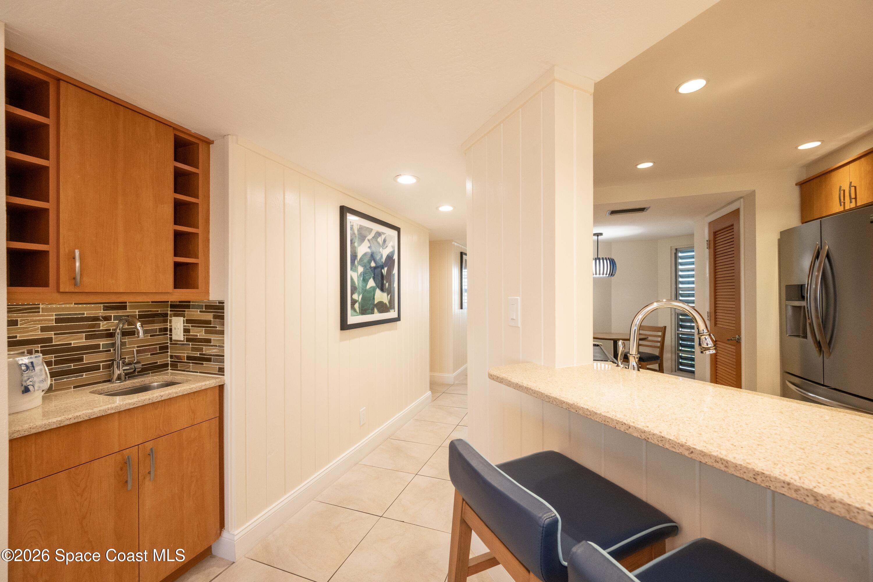 617 Front Street, Unit A52 Key West, FL 33040 - Photo 19 of 42 a kitchen with kitchen island granite countertop a refrigerator oven stove a sink and a dining table with wooden floor