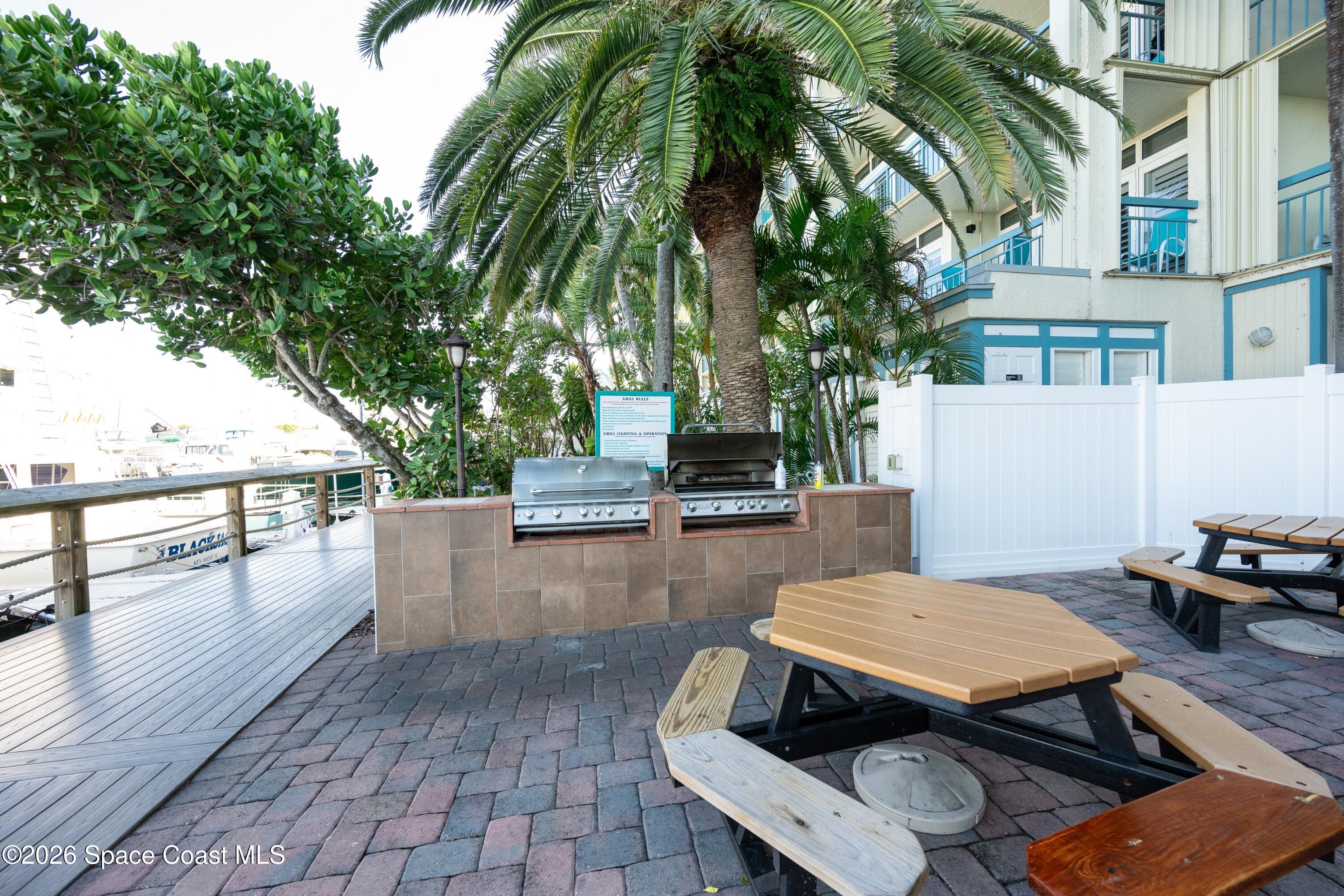 617 Front Street, Unit A52 Key West, FL 33040 - Photo 34 of 42 a view of a patio with table and chairs and potted plants with wooden floor and fence