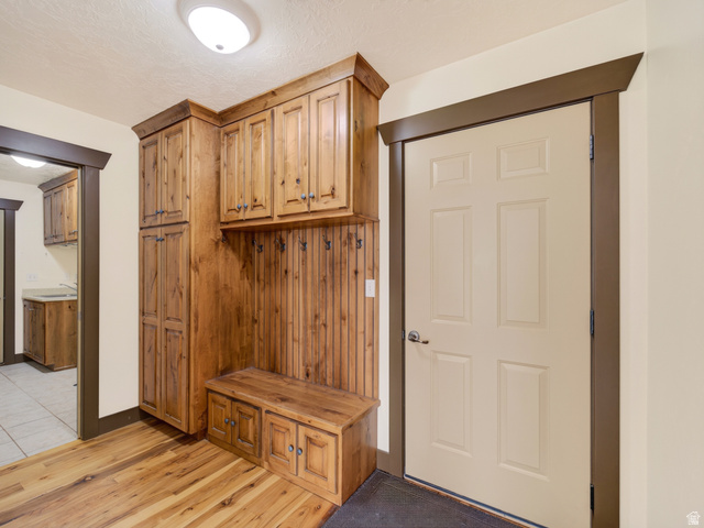 1279 West 1500th Street North Mapleton, UT 84664 - Photo 32 of 83 Entryway featuring wood-finish flooring, built-in storage cabinetry, bench seating with integrated storage, and a paneled entry door with dark trim