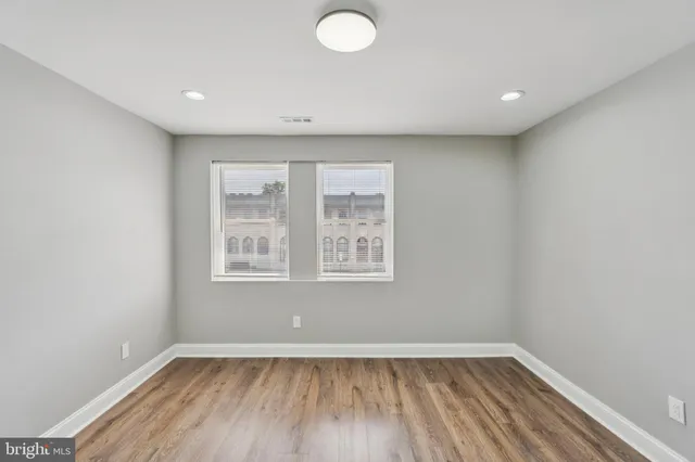 an empty room with wooden floor and windows
