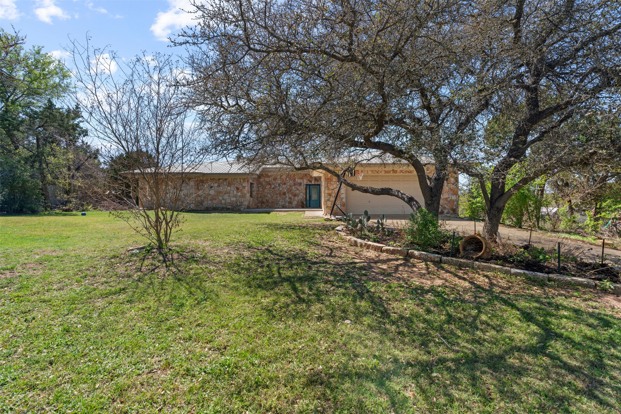 View of front of house with an attached garage, a front lawn, and driveway