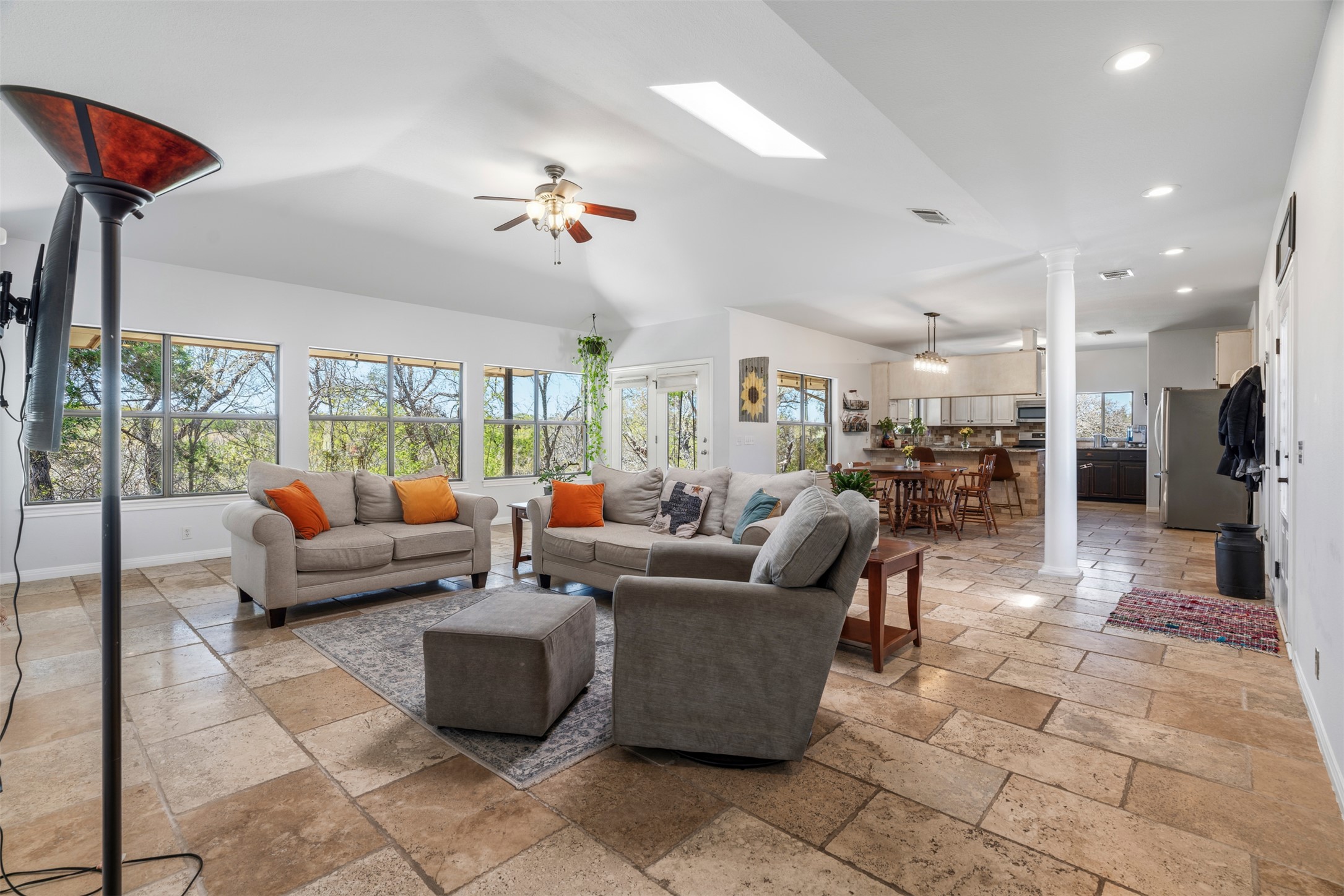 208 Amandas Way Leander, TX 78641 - Photo 2 of 25 Living room featuring stone tile flooring, decorative columns, a ceiling fan, a skylight, and recessed lighting