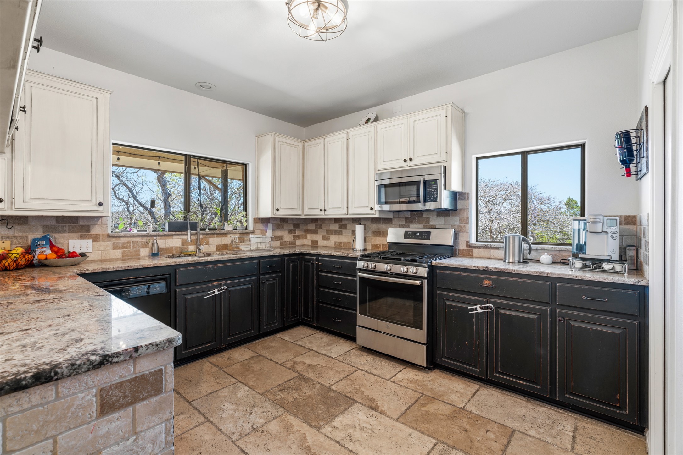208 Amandas Way Leander, TX 78641 - Photo 6 of 25 Kitchen with stainless steel appliances, light stone countertops, two tone cabinetry, stone tile floors, and backsplash