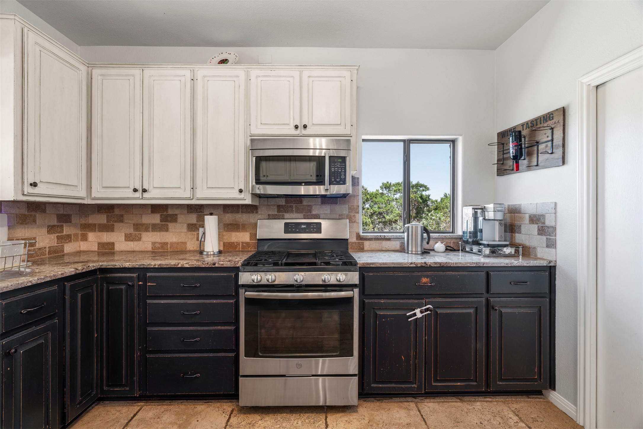 208 Amandas Way Leander, TX 78641 - Photo 7 of 25 Two tone kitchen with stainless steel appliances, two tone cabinetry, decorative backsplash, and light stone countertops
