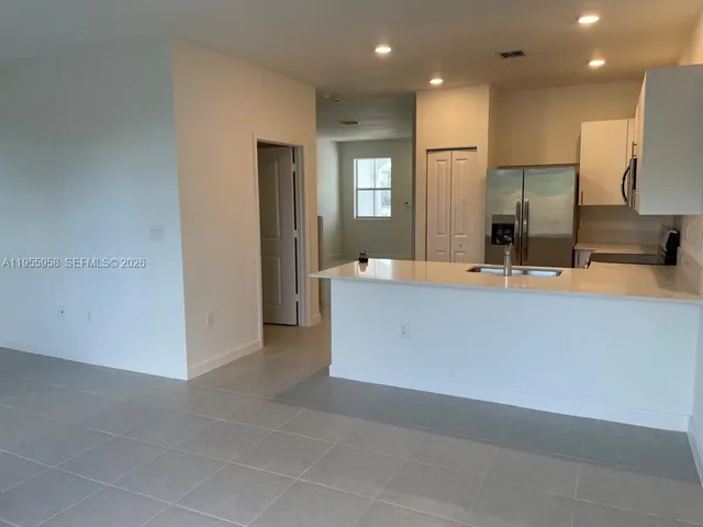 a view of a kitchen with kitchen island a sink wooden floor and a refrigerator