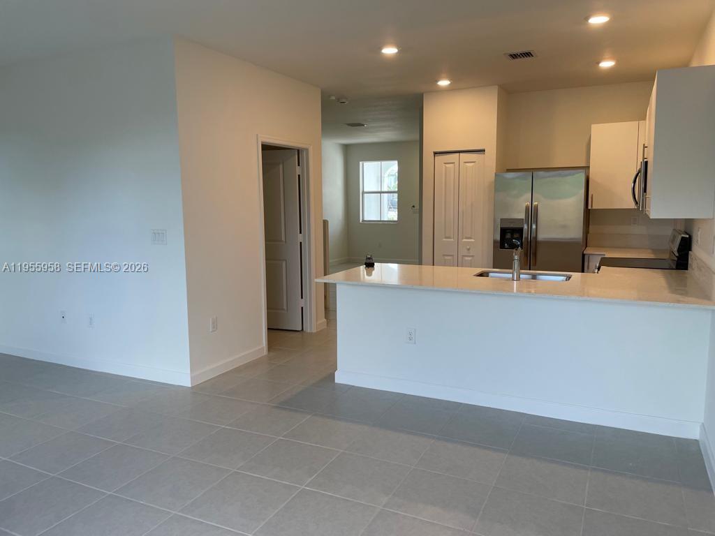 29081 Southwest 162th Court Homestead, FL 33033 - Photo 6 of 18 a view of a kitchen with kitchen island a sink wooden floor and a refrigerator