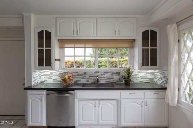 a kitchen with granite countertop white cabinets and stainless steel appliances
