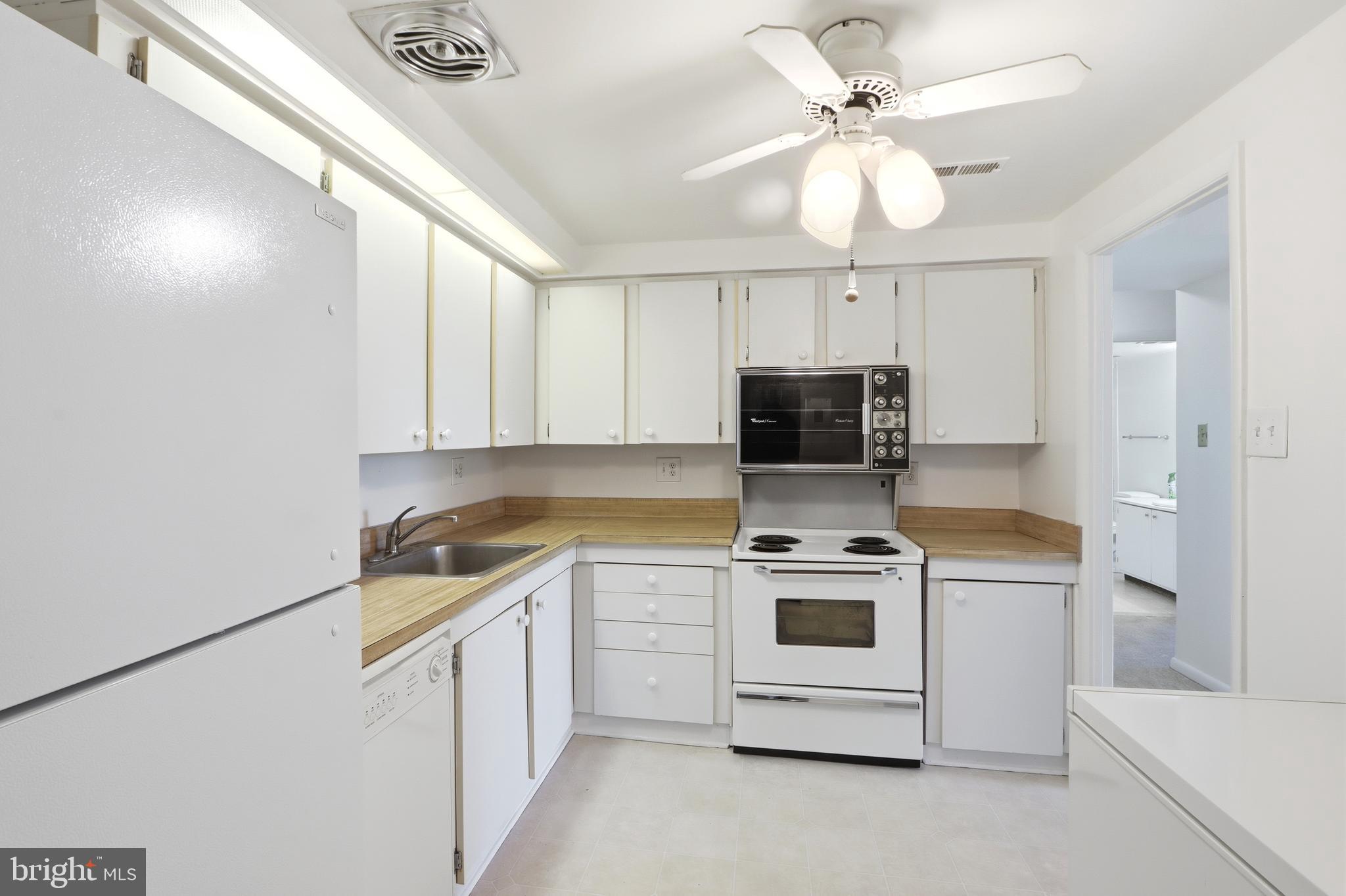 6317 Park Heights Avenue, Unit 404 Baltimore, MD 21215 - Photo 8 of 27 a kitchen with a stove a sink and a refrigerator