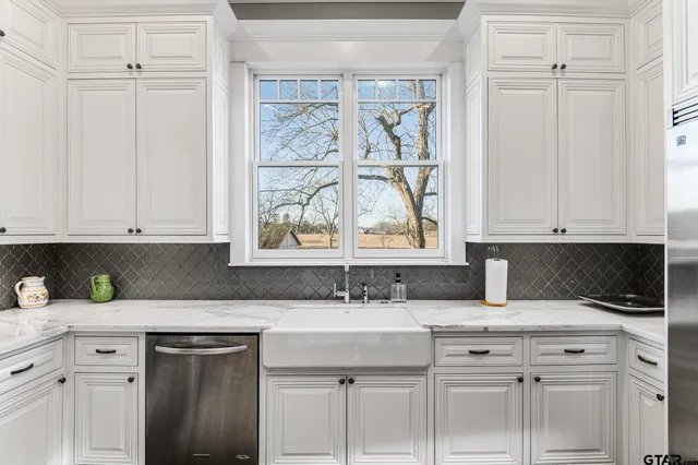 a kitchen with white cabinets and a window