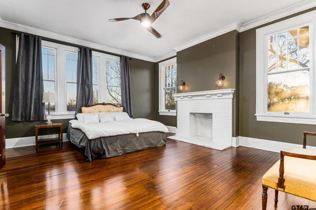 a spacious bedroom with a large bed a chandelier and windows