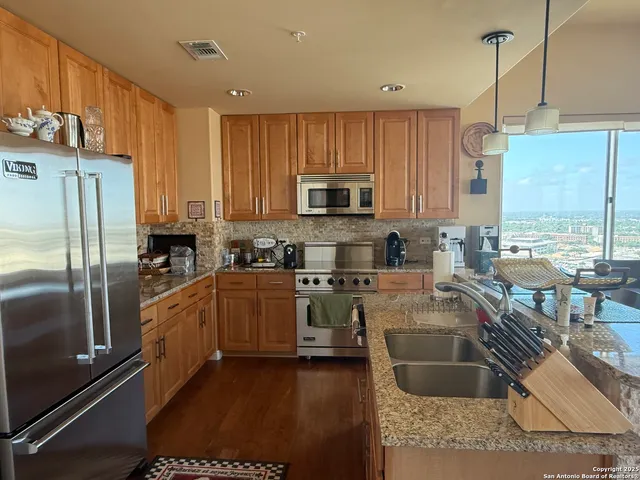 a kitchen with stainless steel appliances granite countertop a refrigerator a stove top oven a sink and dishwasher