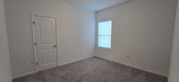 a view of an empty room with closet and a window