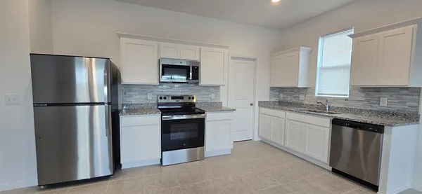 a kitchen with stainless steel appliances granite countertop a refrigerator stove and microwave