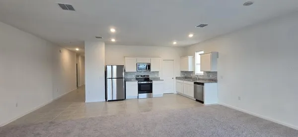 a open kitchen with white cabinets and stainless steel appliances
