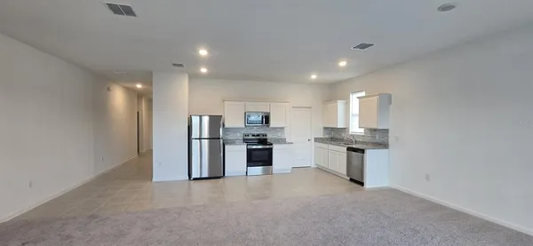 a open kitchen with white cabinets and stainless steel appliances