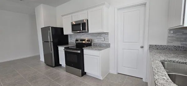 a kitchen with stainless steel appliances granite countertop a refrigerator stove and microwave