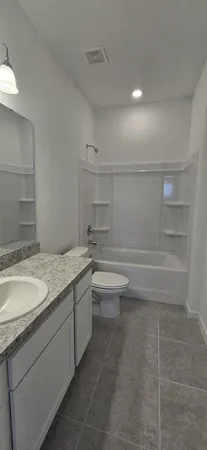 a bathroom with a granite countertop sink a toilet and a mirror