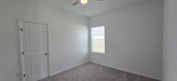 an empty room with a window and chandelier fan