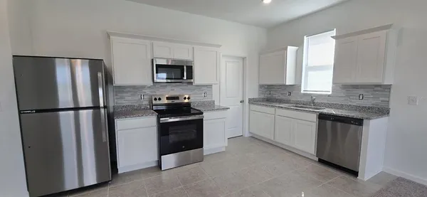 a kitchen with stainless steel appliances granite countertop a refrigerator sink and stove