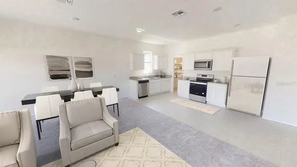 a living room with furniture a refrigerator and kitchen view