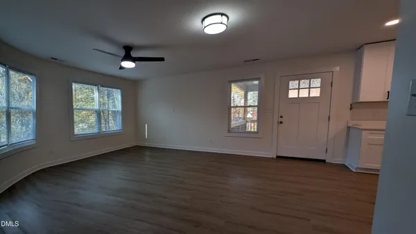 a view of an empty room with wooden floor and a window