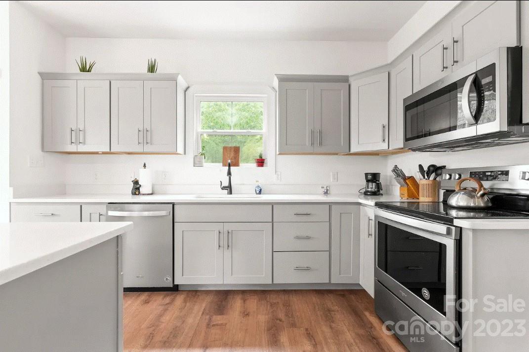 231 Medford Branch Road Candler, NC 28715 - Photo 11 of 28 a kitchen with stainless steel appliances granite countertop a stove a sink cabinets and a microwave oven