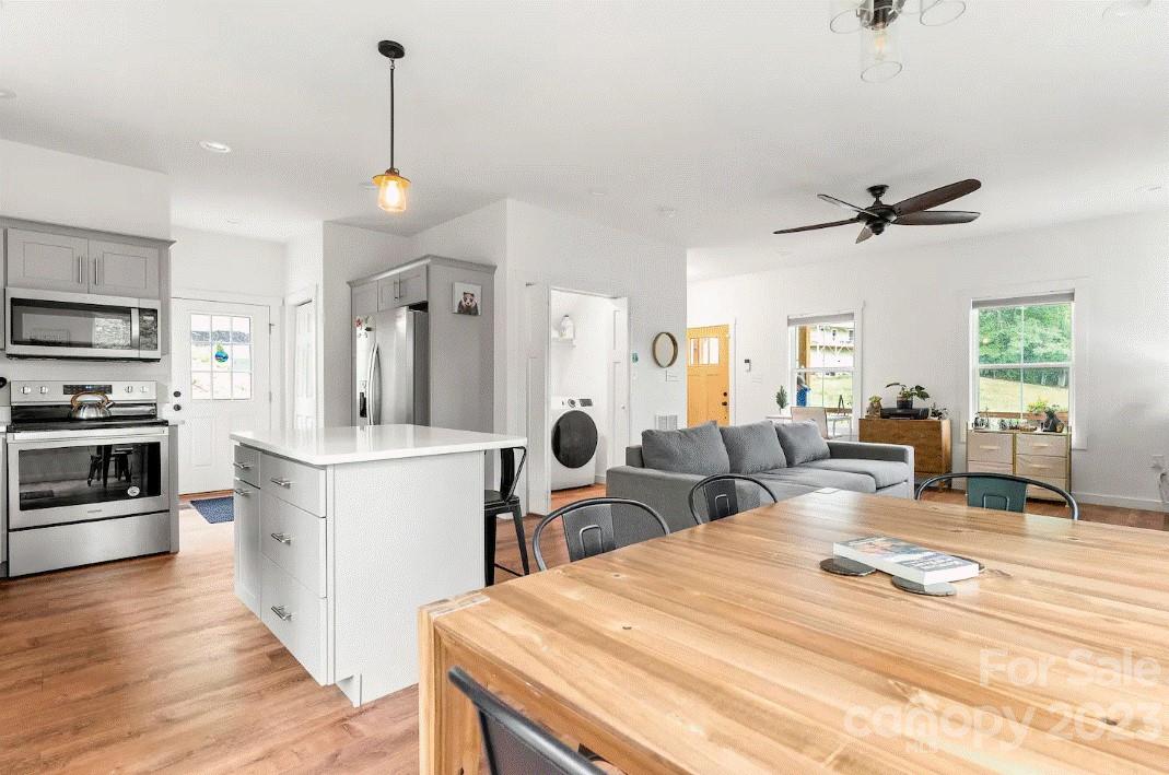 231 Medford Branch Road Candler, NC 28715 - Photo 14 of 28 a kitchen with stainless steel appliances kitchen island granite countertop a sink cabinets and wooden floor