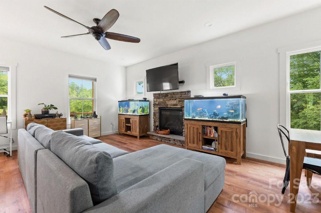 231 Medford Branch Road Candler, NC 28715 - Photo 5 of 28 a living room with furniture a flat screen tv a window and a fireplace