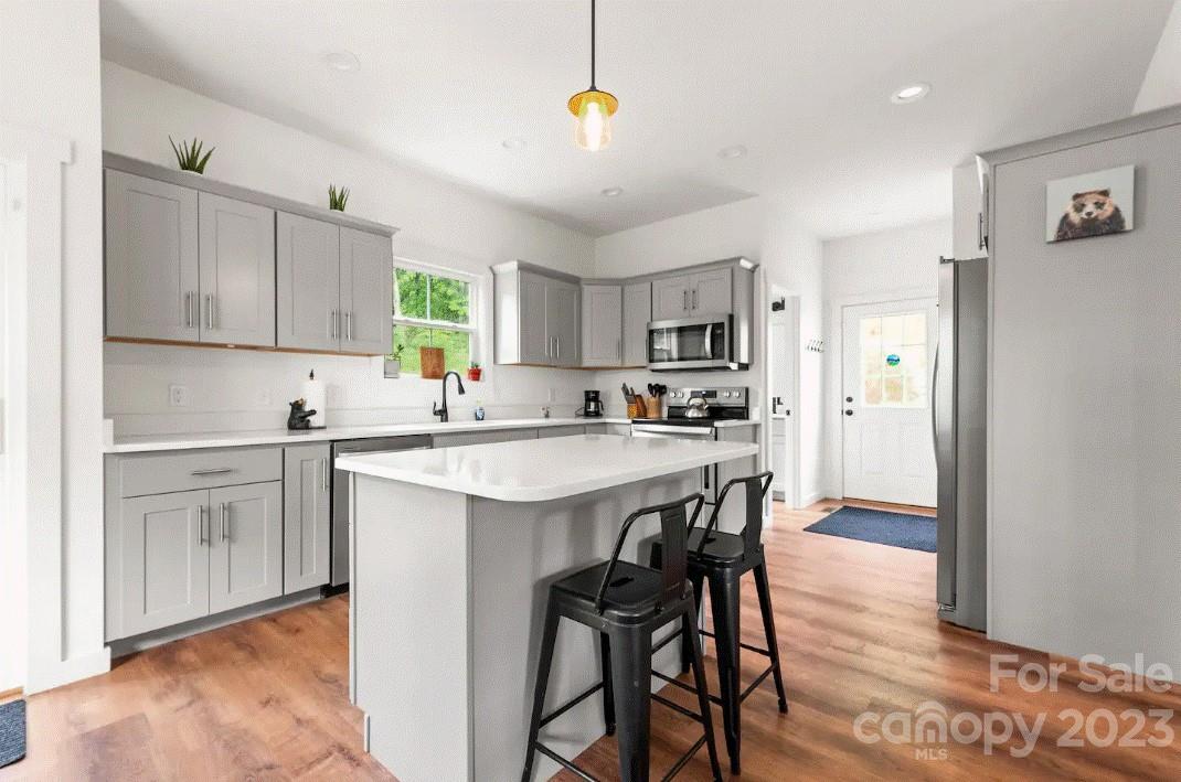 231 Medford Branch Road Candler, NC 28715 - Photo 8 of 28 a kitchen with stainless steel appliances kitchen island a white counter top space cabinets and a window