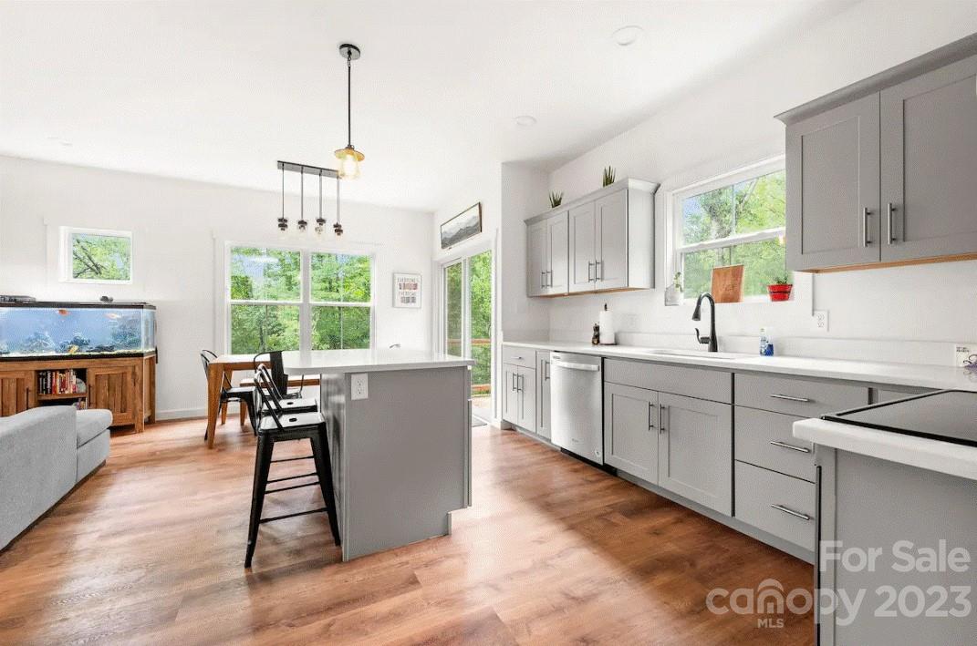 231 Medford Branch Road Candler, NC 28715 - Photo 9 of 28 a kitchen with stainless steel appliances granite countertop a stove top oven a sink dishwasher a dining table and chairs with wooden floor