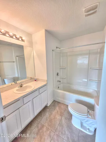 a bathroom with a granite countertop bathtub shower sink vanity and toilet