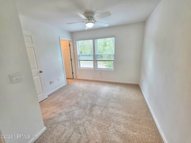 an empty room with windows and fan
