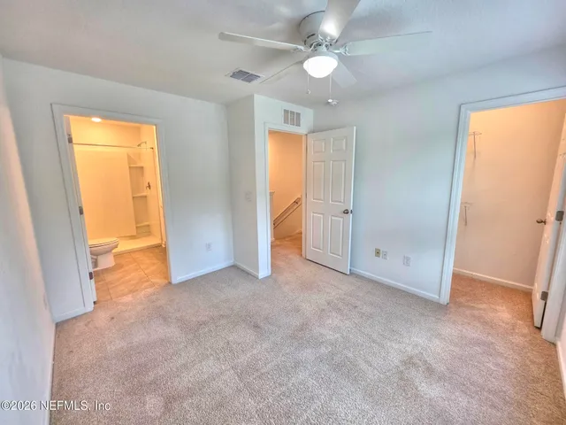 an empty room with closet and a ceiling fan
