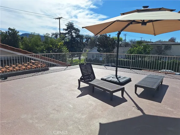 a view of a roof deck with couches under an umbrella
