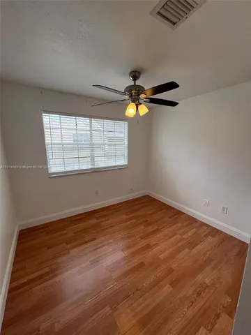 an empty room with window and chandelier fan