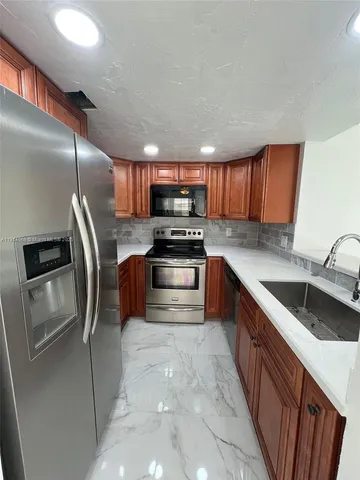 a kitchen with granite countertop a sink stainless steel appliances and cabinets