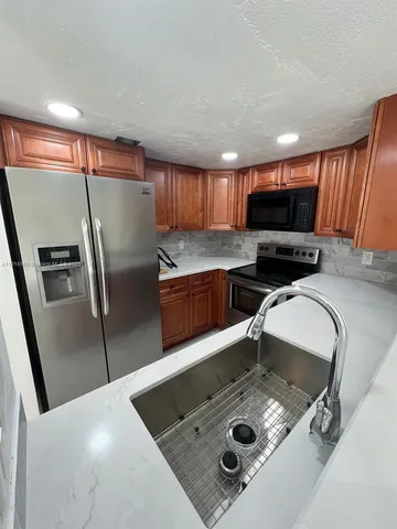 a kitchen with stainless steel appliances granite countertop a sink refrigerator and microwave