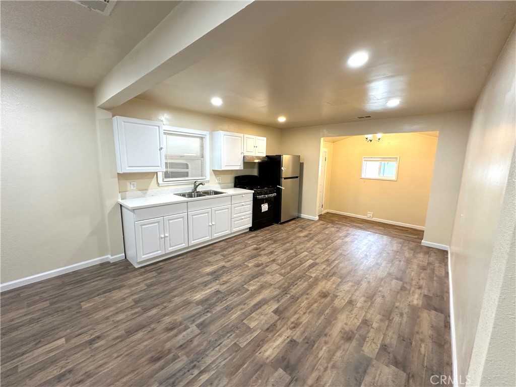 828 West 23rd Street Merced, CA 95340 - Photo 6 of 19 a view of a kitchen with kitchen island a sink wooden floor and a refrigerator