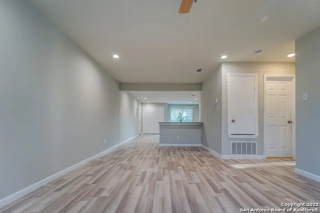 a view of empty room with wooden floor and kitchen
