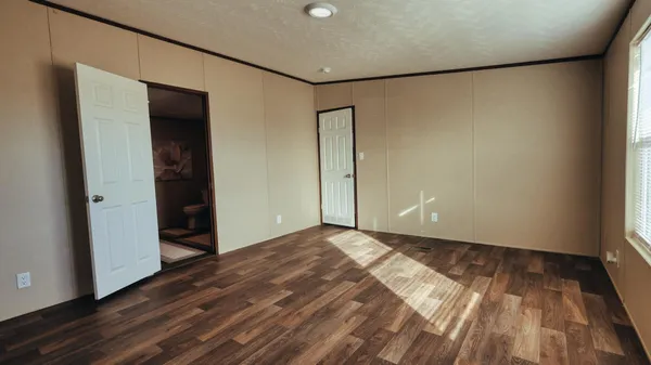 a view of an empty room with wooden floor and closet