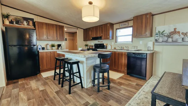 a kitchen with stainless steel appliances granite countertop a stove a refrigerator a sink a dining table and chairs with wooden floor