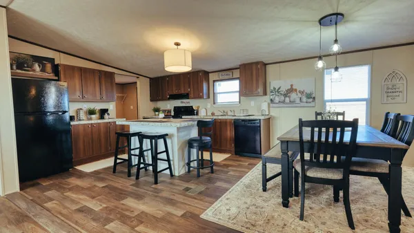 a kitchen with stainless steel appliances kitchen island granite countertop a table chairs and a refrigerator