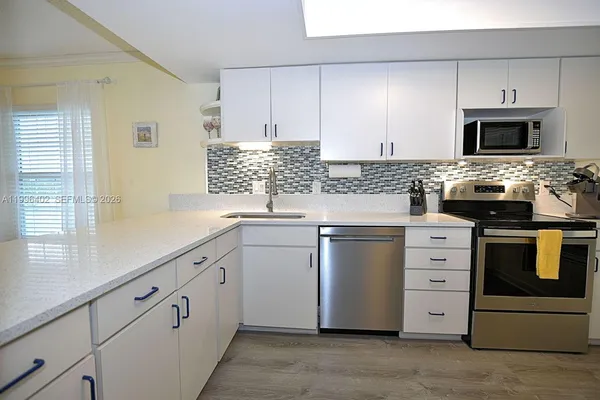 a kitchen with white cabinets stainless steel appliances and sink