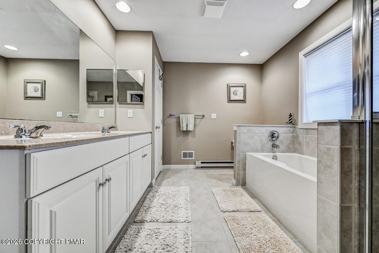 151 Skytop Road Long Pond, PA 18334 - Photo 21 of 36 a spacious bathroom with a double vanity sink a mirror and a bathtub