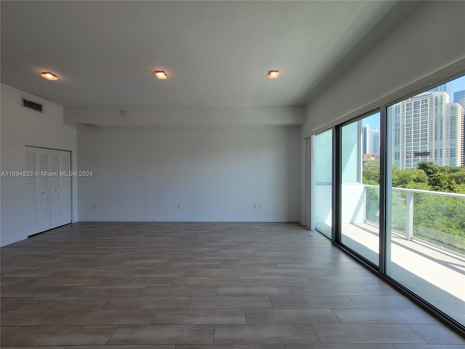 1600 Southwest 1st Avenue, Unit 411 Miami, FL 33129 - Photo 6 of 15 an empty room with wooden floor and windows